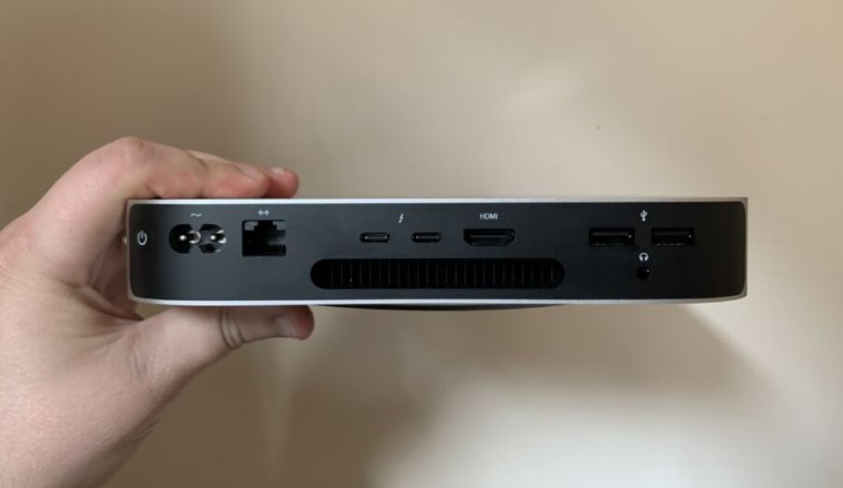 An M1 Mac Mini, held in hand.