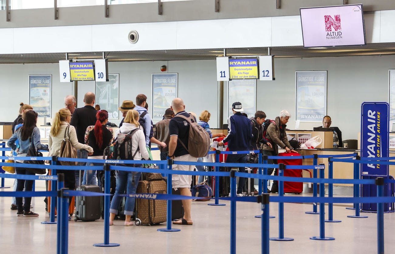 Passengers in line at a Ryanair check-in desk.