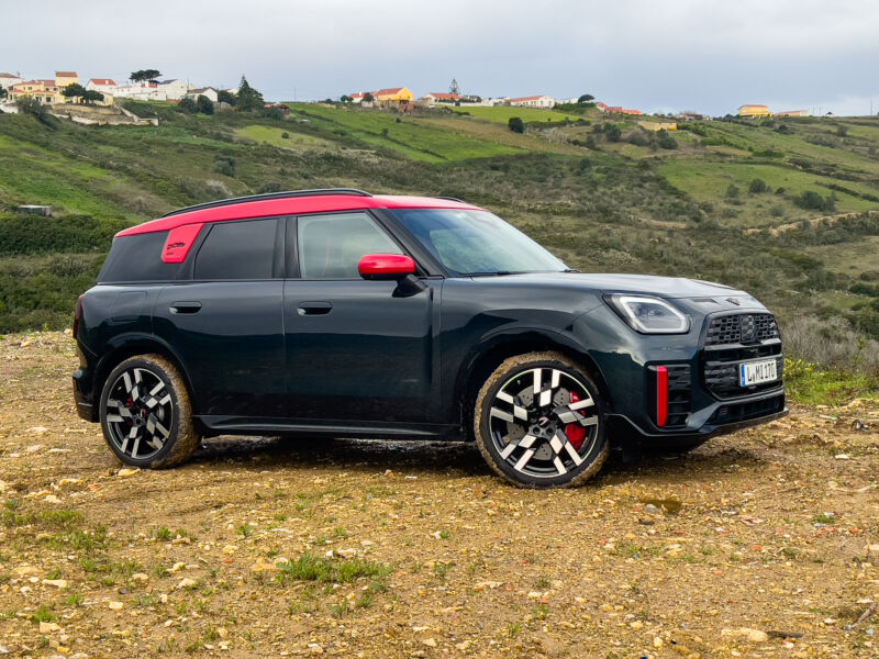 A black and red Mini JCW Countryman parked on some bare ground