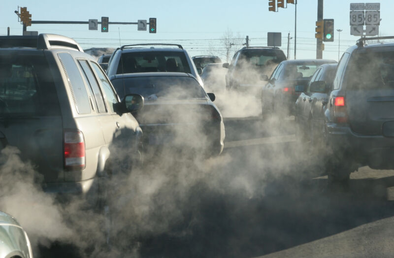 At an intersection in Denver, Colorado, exhaust pours out of a tailpipes from accelerating vehicles onto Santa Fe Drive.