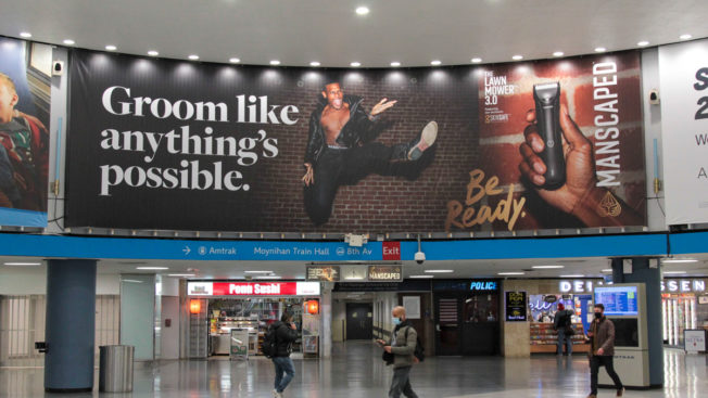 a large ad in a train station that says "groom like anything's possible"