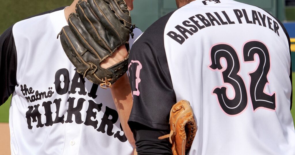 Two baseball players in the MiLB sporting Oat Milkers jerseys.