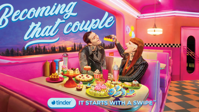 a couple sitting in a neon diner feeding each other