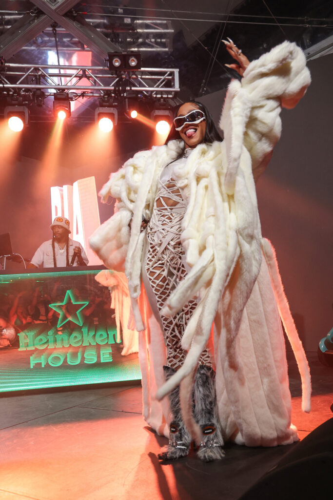 rapper BIA in a fur coat smiling onstage at Heineken House