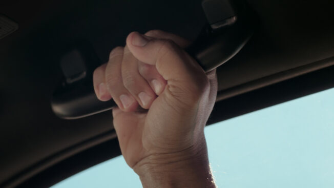 A car passenger grips a Toyota Tacoma's grab handle.