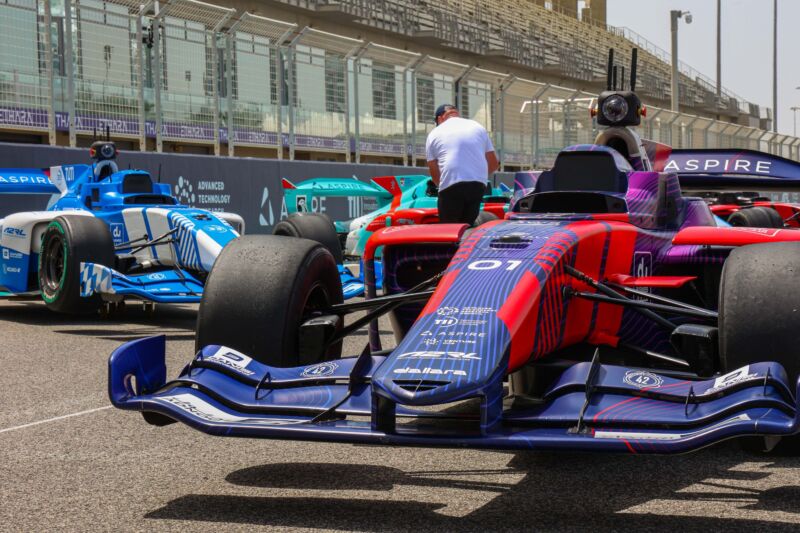Several brightly colored race cars are parked at a race course