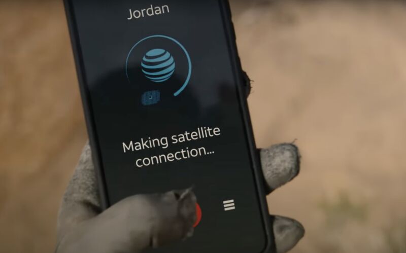 A gloved hand holds a phone while making a call. The screen shows an AT&T logo and the text, 