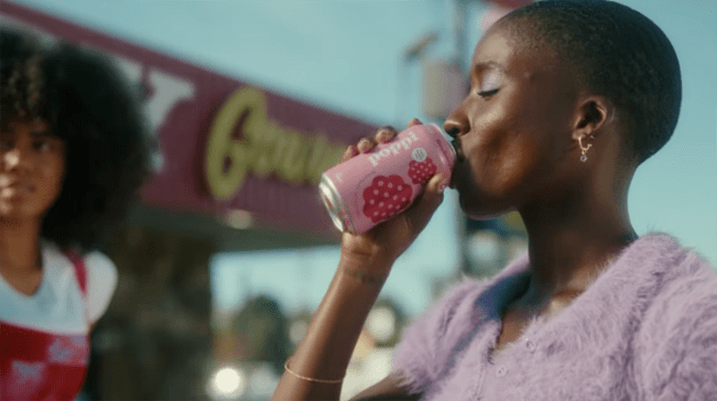 a woman drinking a can of Poppi soda