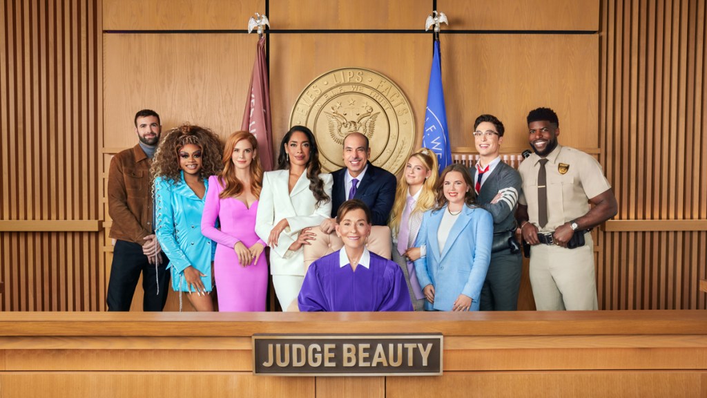 Judge Judy and a bunch of other celebrities smiling on a judge's bench