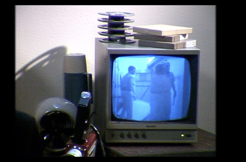 A prop TV displays scenes from inside the recreation set hallway.