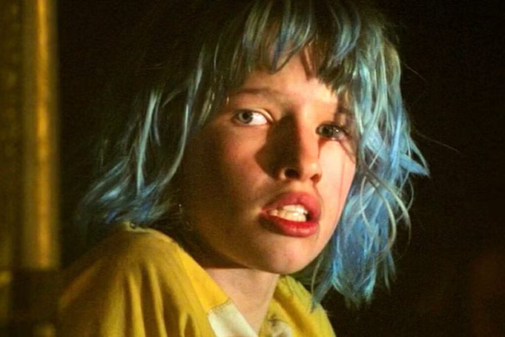 frightened young girl with dyed blue hair and a yellow shirt.