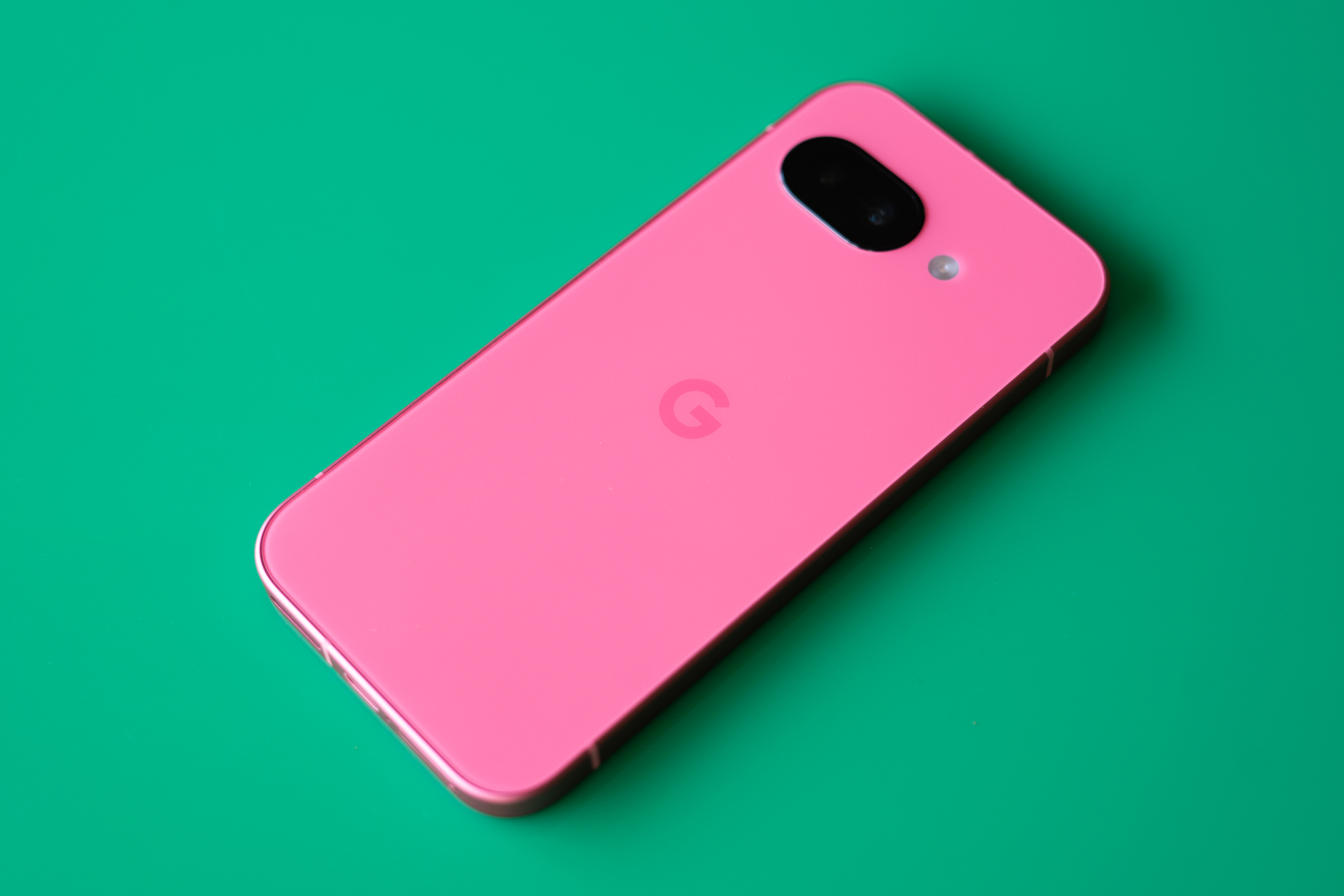 Google Pixel 9A in peony pink on a green background