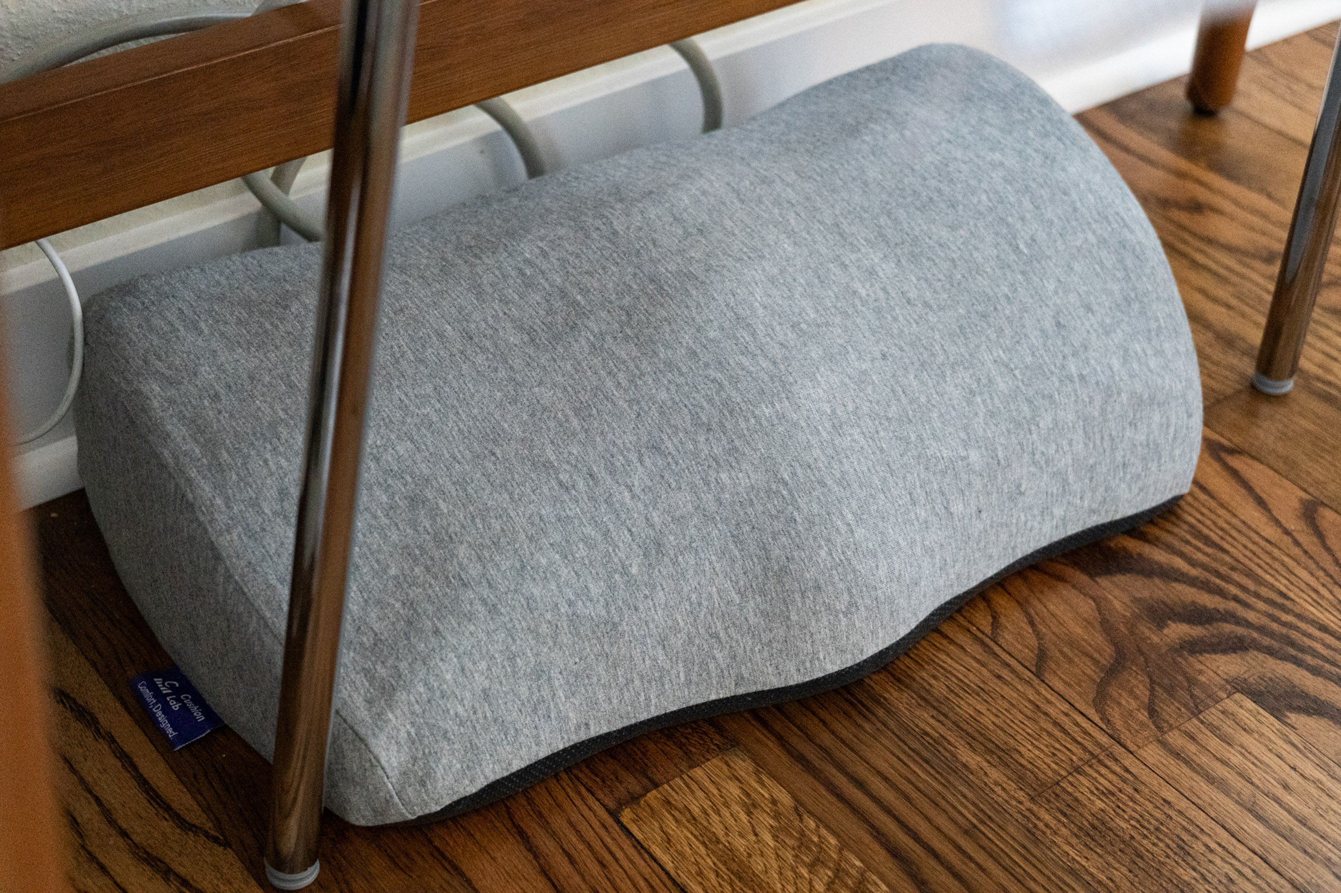Gray foot rest underneath a desk.
