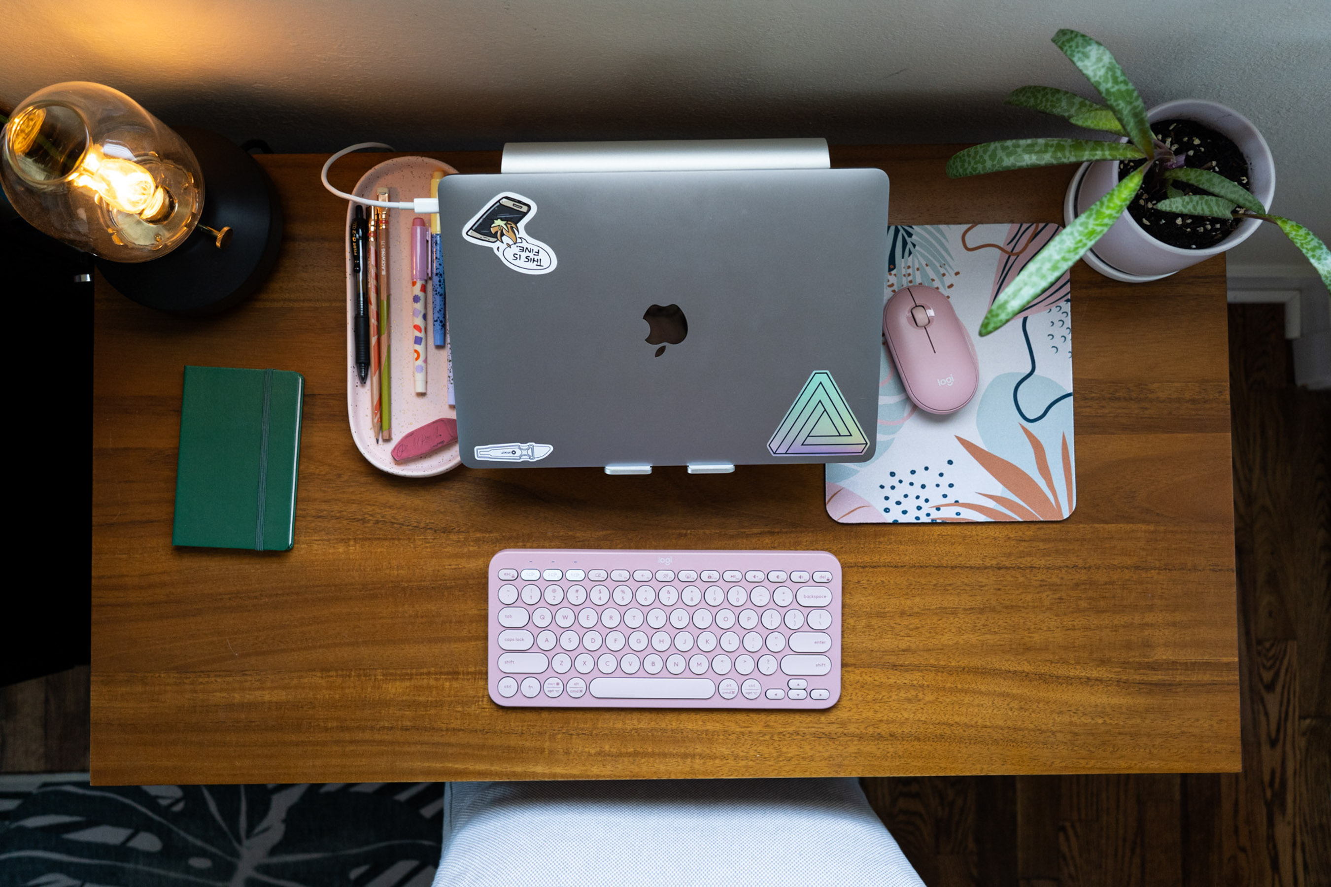 Looking down on a desk showing a laptop on a stand and a keyboard.