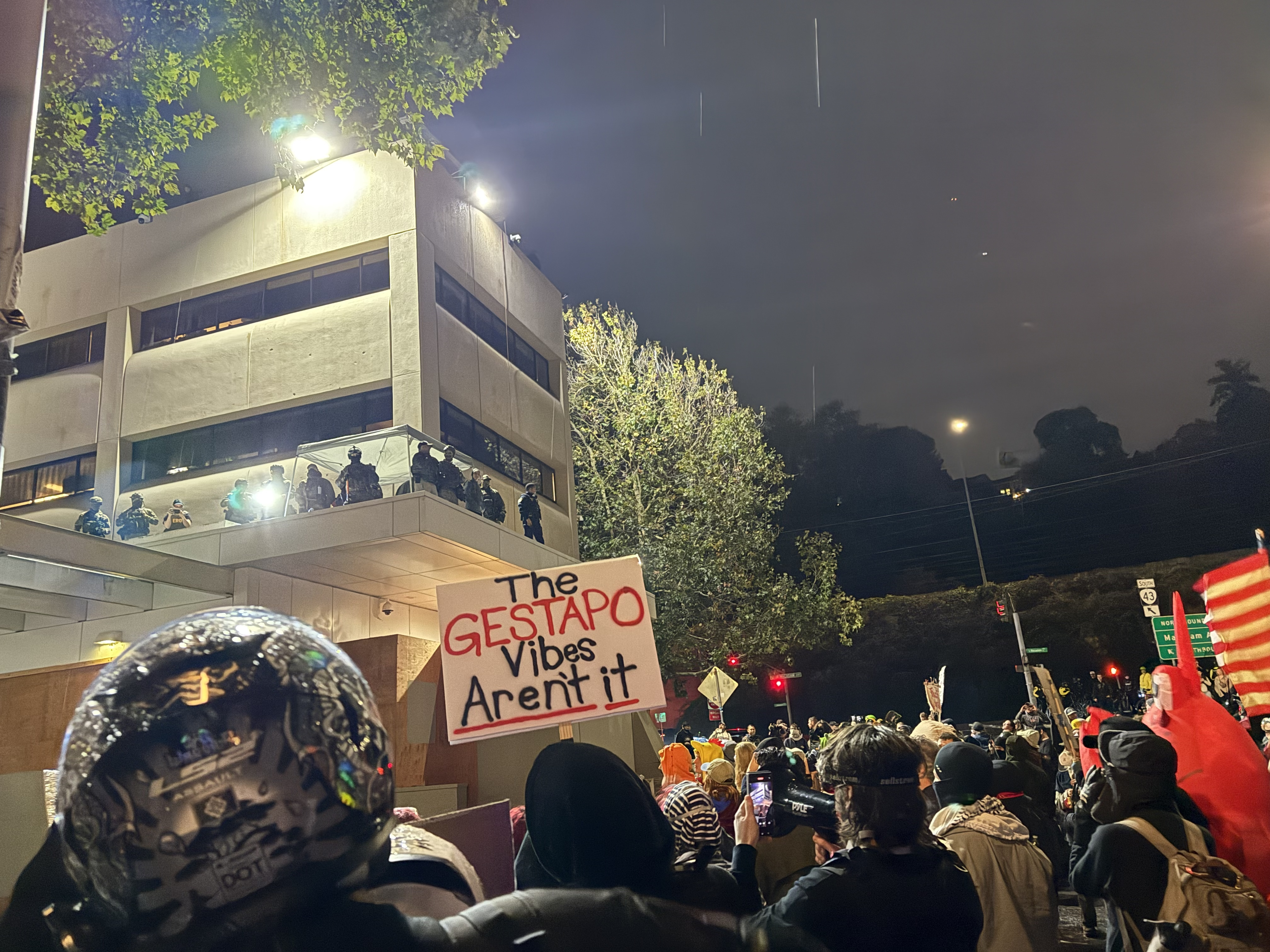Federal law enforcement looms over a crowd at the ICE building in southwest Portland.