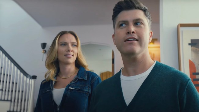 Scarlett Johnansson looks at Colin Jost as they stand in a living room