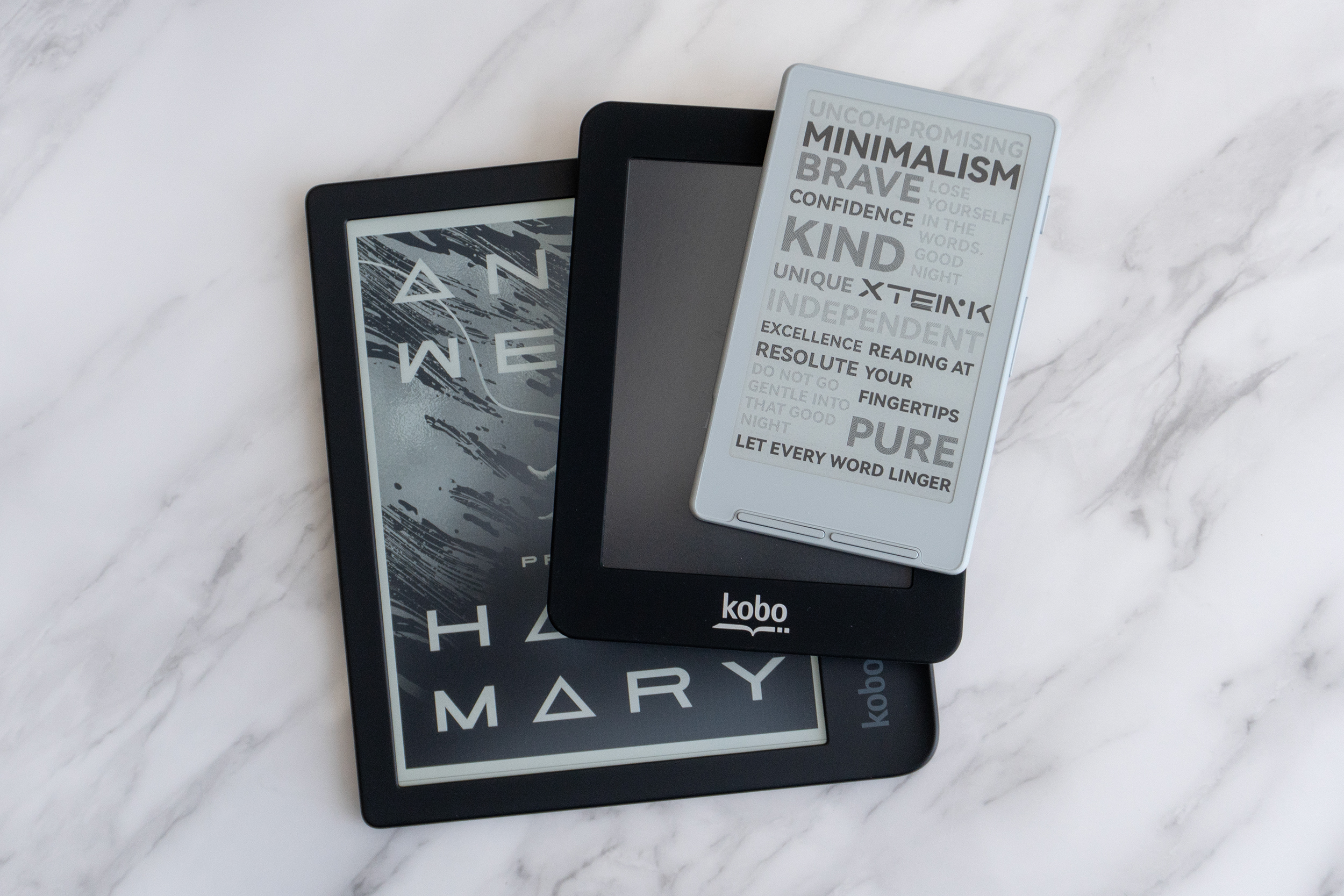 The Xteink X4 e-reader on top of two smaller Kobo e-readers.