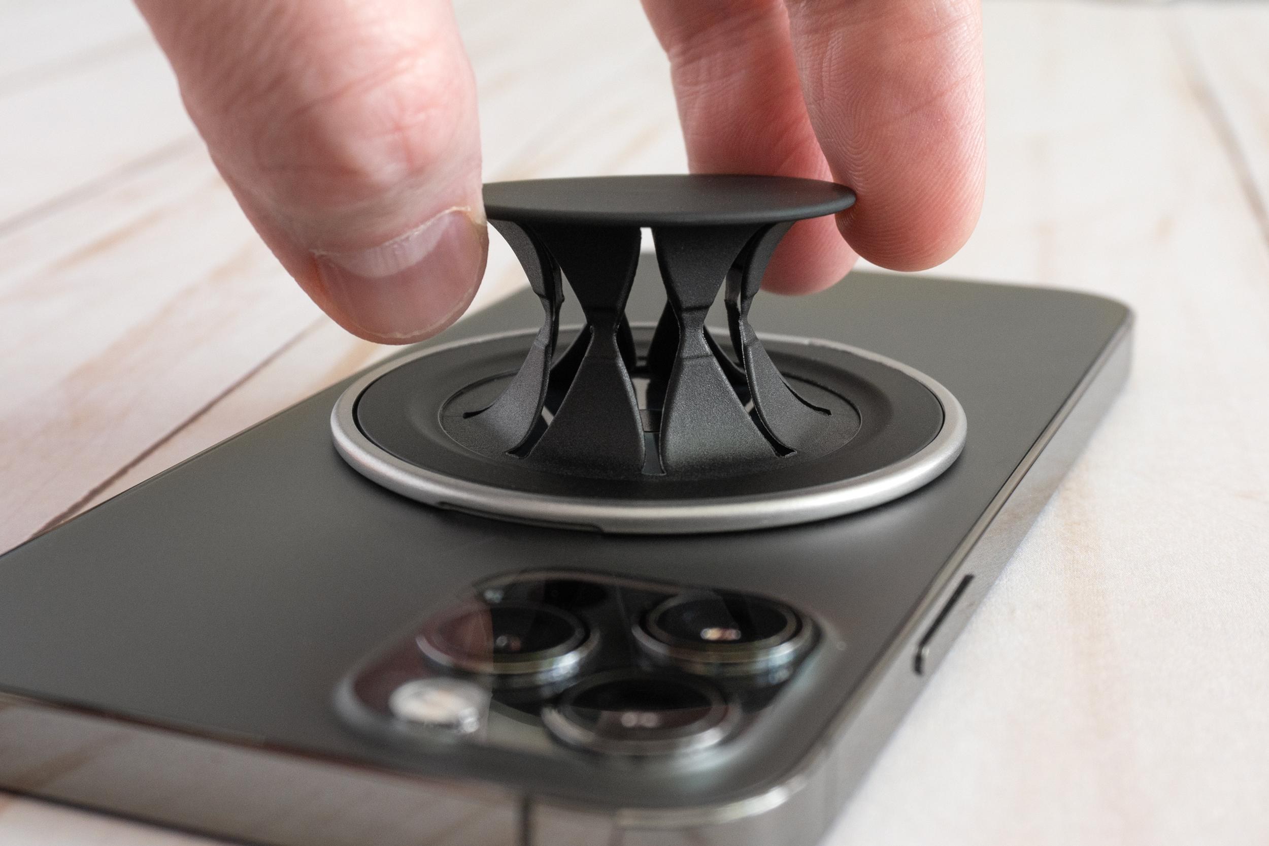 A person extends the PopSockets Low-Pro revealing how its outer cap connects to the base of the grip.