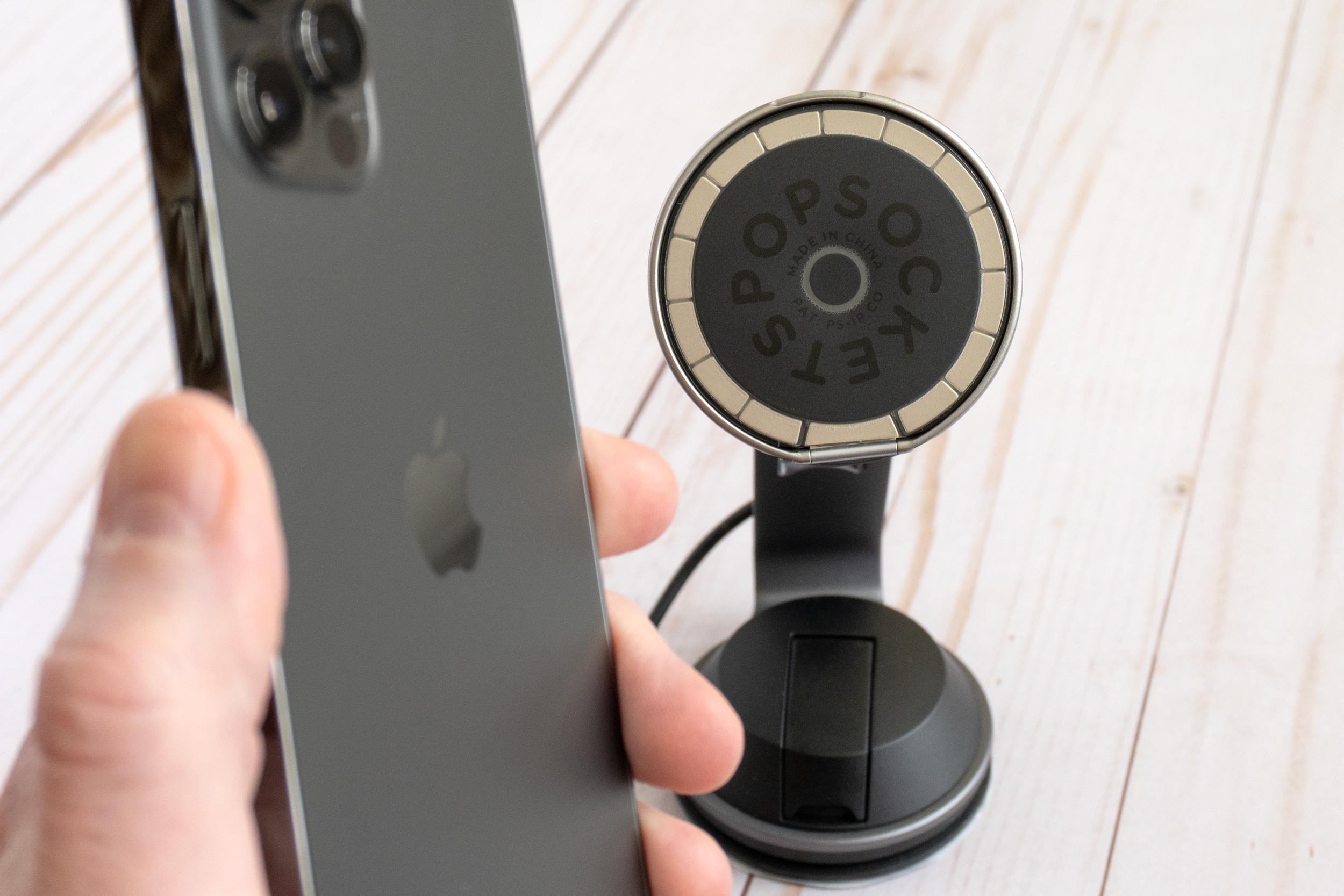 A person holding an iPhone 12 Pro with the PopSockets Low-Pro grip stuck to a magnetic phone charger.