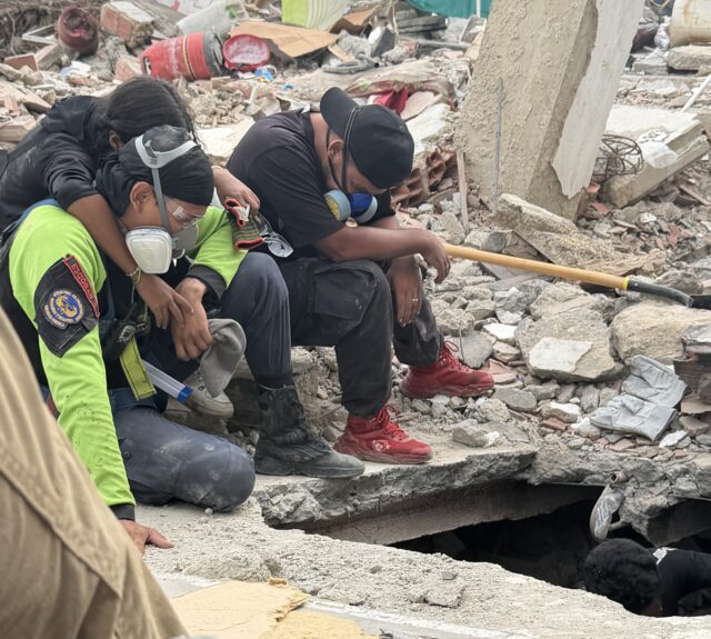 Mexican search and rescue workers from the Los Topos volunteer group sit near a hole while looking for people in collapsed building debris in Venezuela, following two earthquakes that struck on June 24.