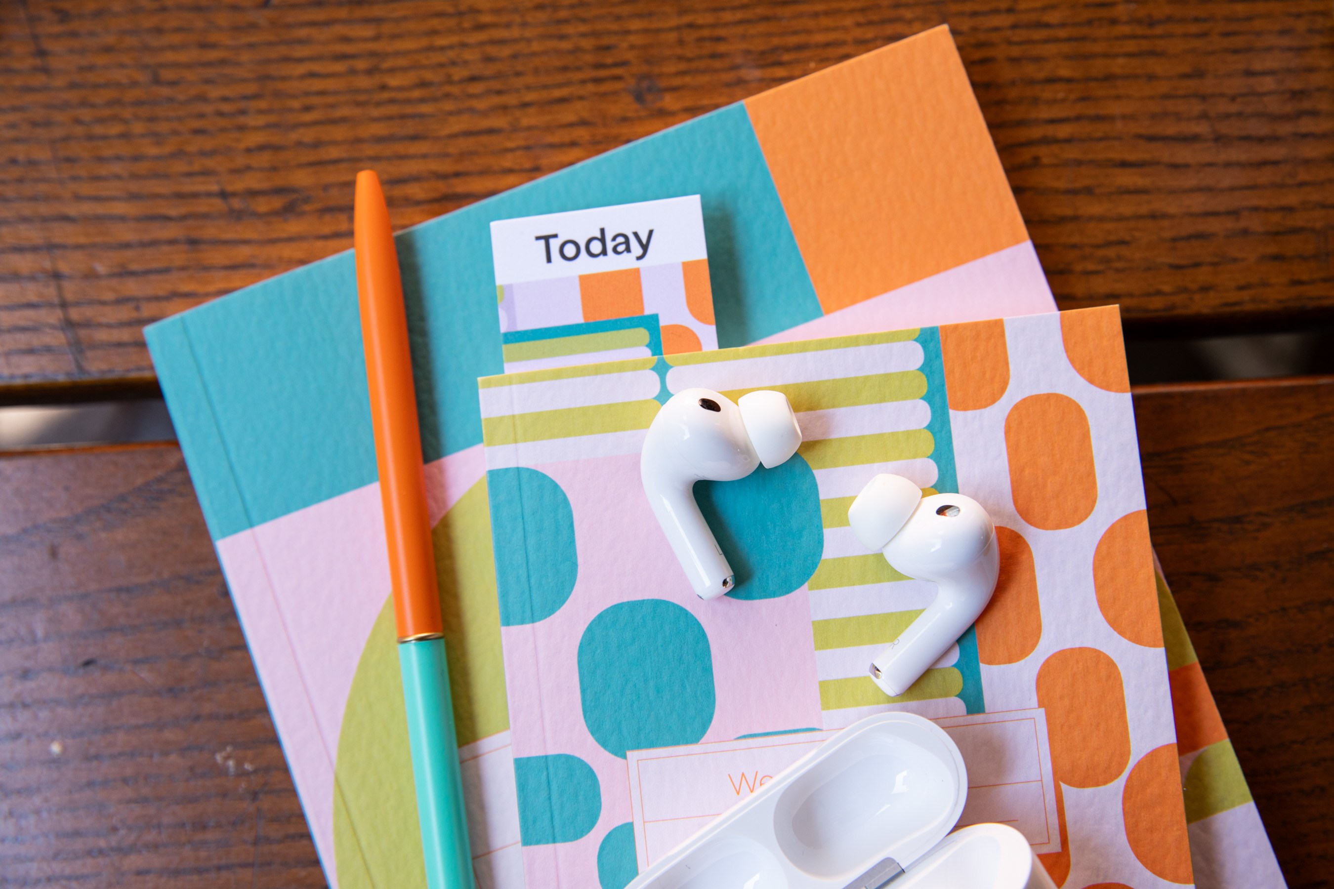 AirPods Pro 3 on some colorful notebooks.