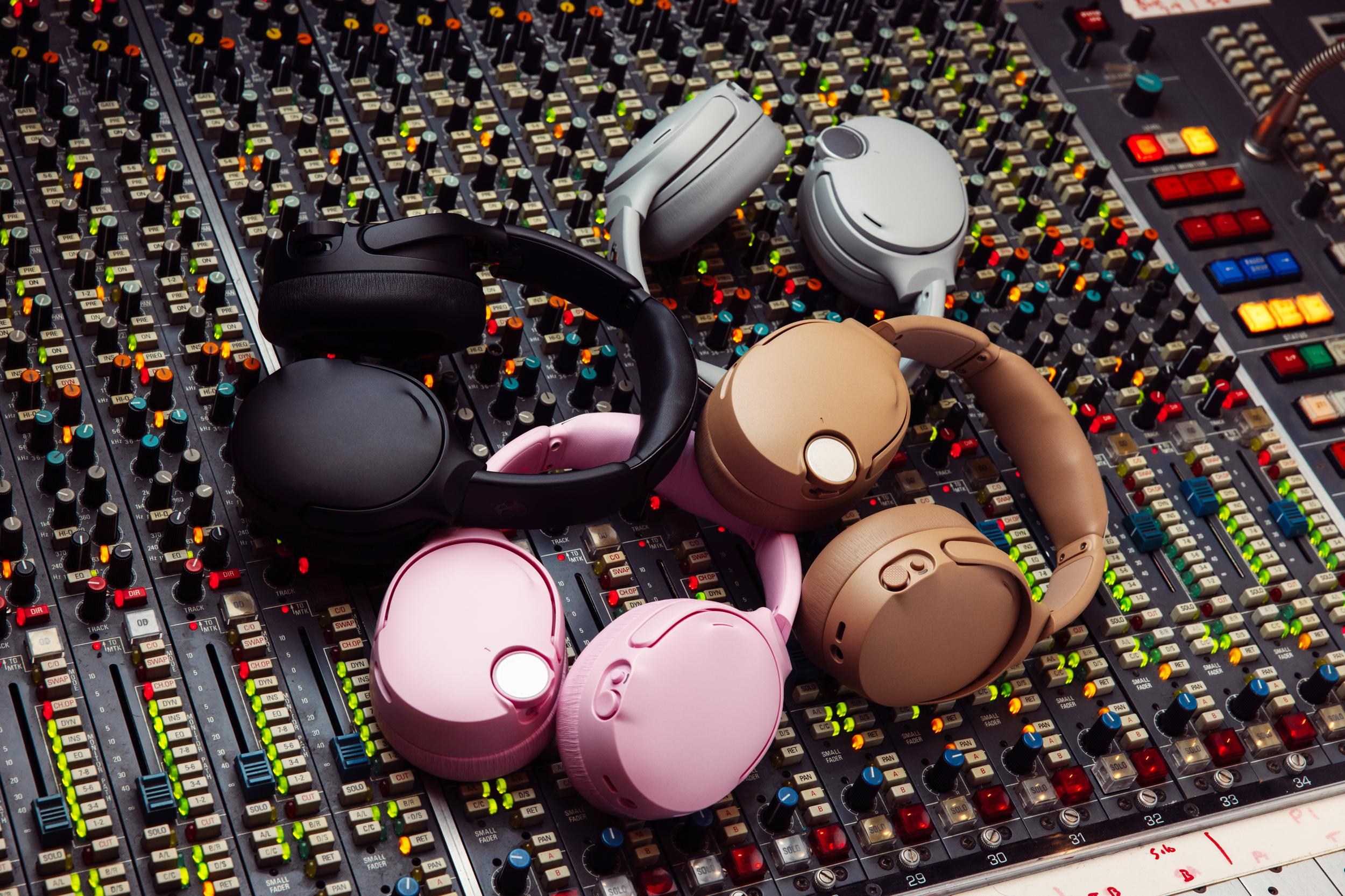 A pile of Skullcandy headphones sitting on a mixing board in a studio.