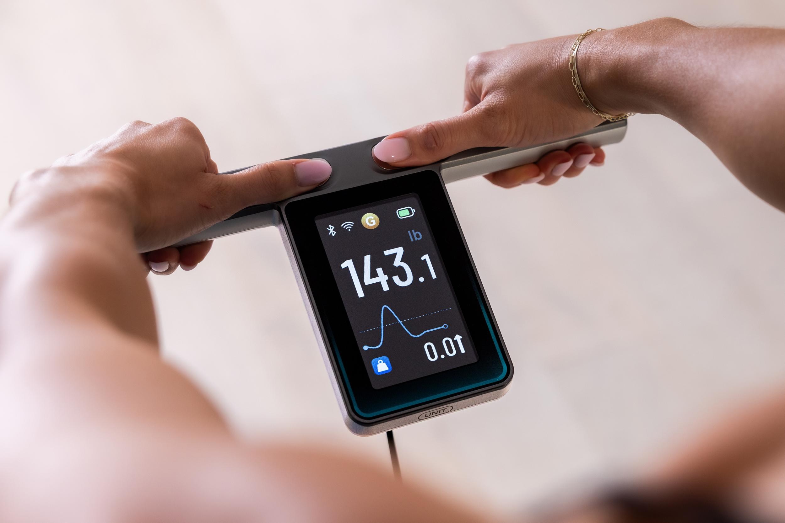 A person holds the screen-equipped handle on the Wyze Scale Ultra BodyScan Plus.